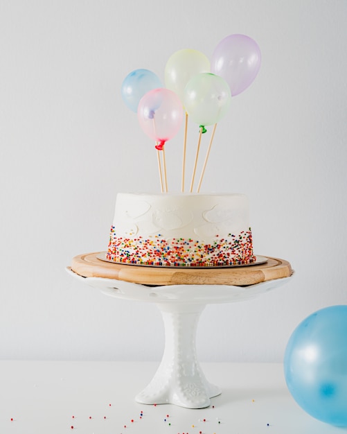 Witte verjaardagstaart en kleurrijke ballonnen