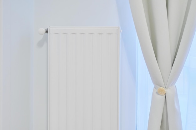 Witte verwarmingsradiator met temperatuurthermostaat in het interieur van het appartement