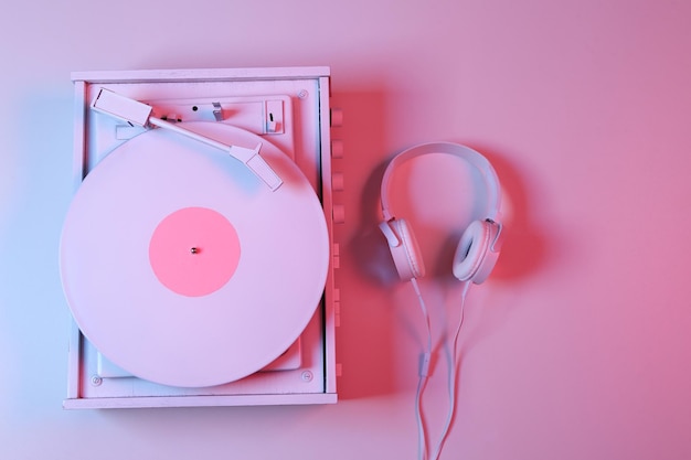 Witte vinylplatenspeler met koptelefoon in rozeblauw neonverlooplicht Minimalisme muziekconcept Bovenaanzicht
