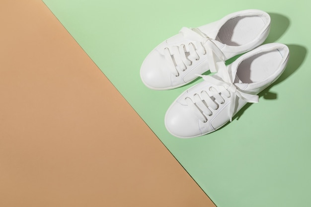 Witte vrouwelijke gumshoes op een beige achtergrond