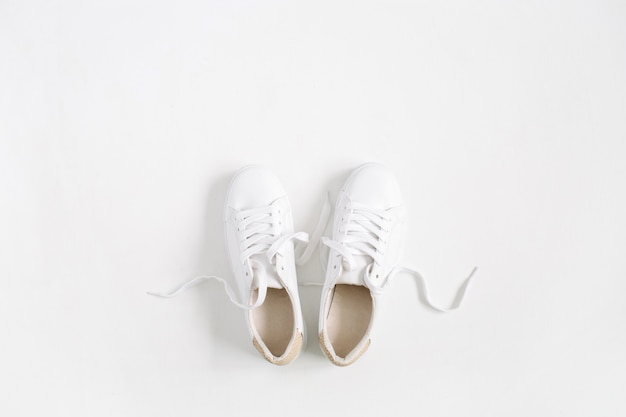 Witte vrouwelijke sneakers geïsoleerd op een witte achtergrond. Platliggend, bovenaanzicht