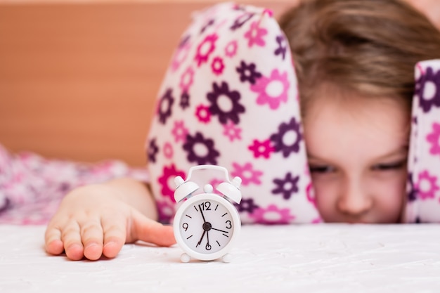 Witte wekker staat op de tafel van een wakker meisje