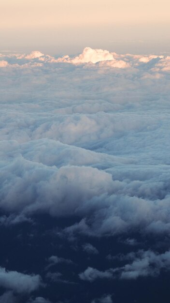 Witte wolken en blauwe lucht met geel warm zonlicht vanuit het vliegtuigraam.