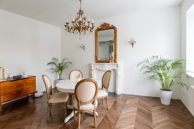 Witte woonkamer met klassieke inrichting, spiegel, open haard, eettafel.