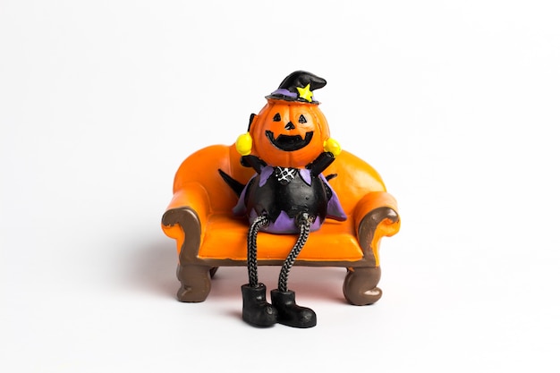 Wizard pumpkin halloween sitting on a orange sofa.