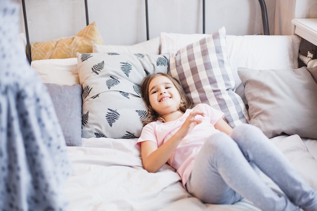 wo meisjes, zussen vechten kussens op het bed, het raam versierd met een kerstkrans, leven, jeugd