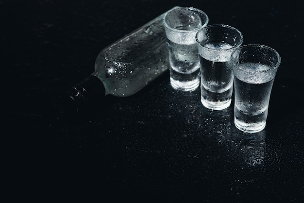 Foto wodka. shots, glazen met wodka met ijs. donkere achtergrond. ruimte kopiëren. selectieve focus