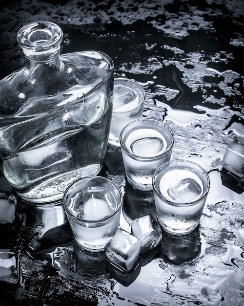 Foto wodka-shots met ijs. op het zwarte bord.