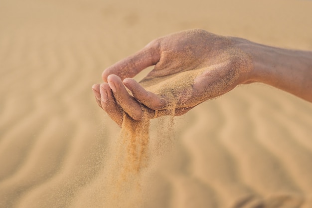 Foto woestijn, zand blaast door de vingers van een mannenhand