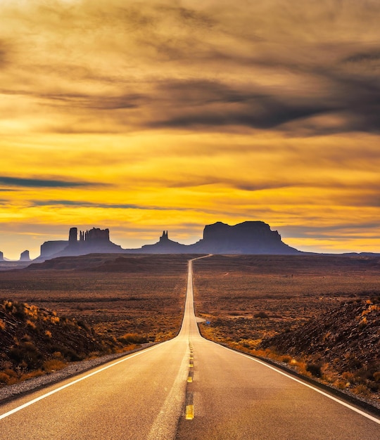 Woestijnweg die bij zonsondergang naar monument valley leidt