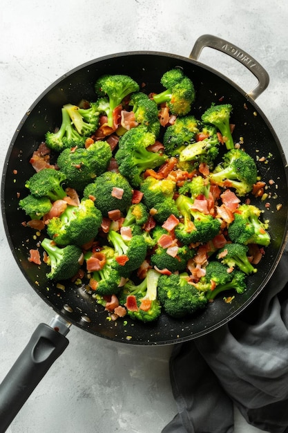 A wok of broccoli florets with diced prosciutto on a white