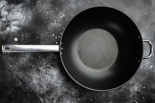 Wok pan empty set with copy space for text or food with copy\
space for text or food, top view flat lay, on black dark stone\
table background