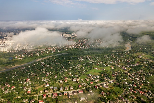 wolken boven een dorp tussen groene velden