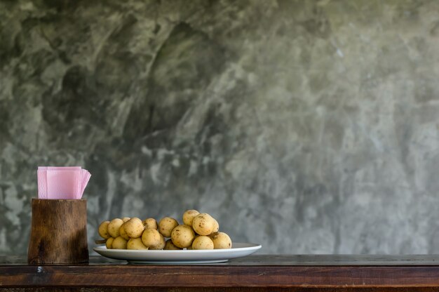 Photo wollongong in the plate with tissues paper on the wood table with brick wall background