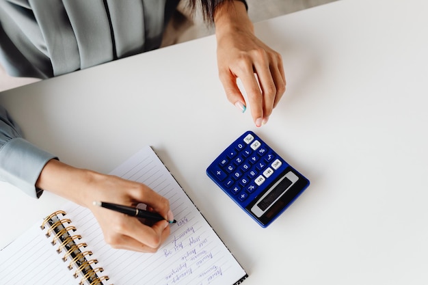 Woman accountant use calculator and computer with holding pen on desk in office. finance and account