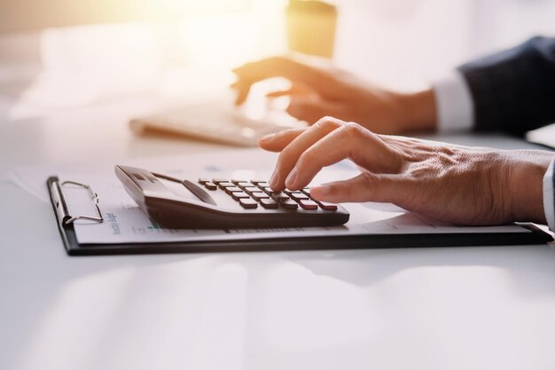 Woman accountant use calculator and computer with holding pen on