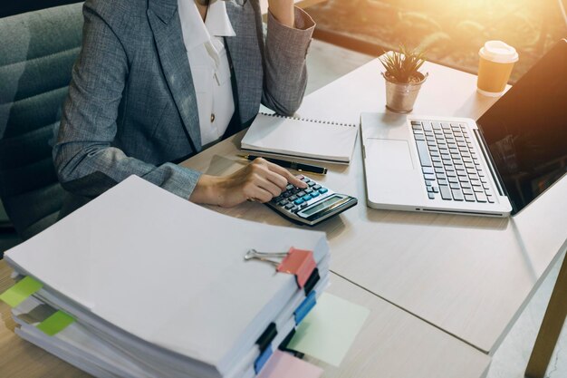 Woman accountant use calculator and computer with holding pen on