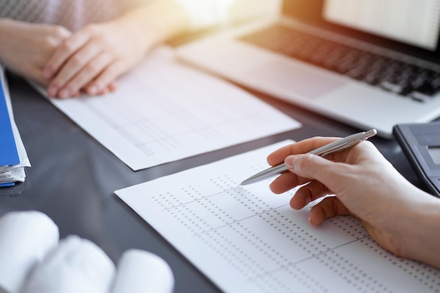 Woman accountant using a calculator and laptop computer while counting taxes for a client. Business audit concepts.