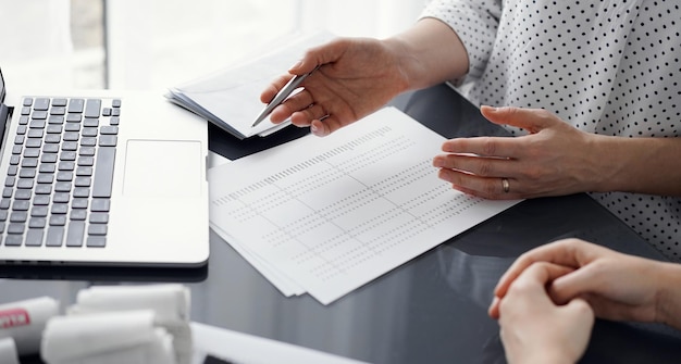 Woman accountant using a calculator and laptop computer while counting taxes for a client. Business audit and finance concepts