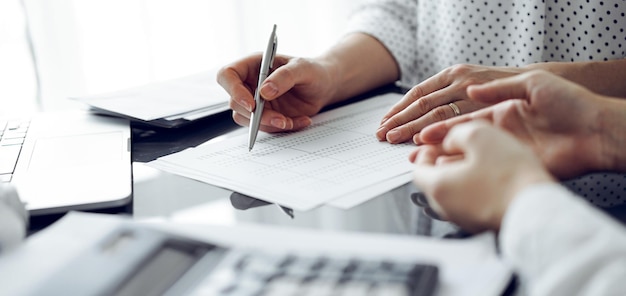 Woman accountant using a calculator and laptop computer while counting taxes for a client. Business audit and finance concepts.