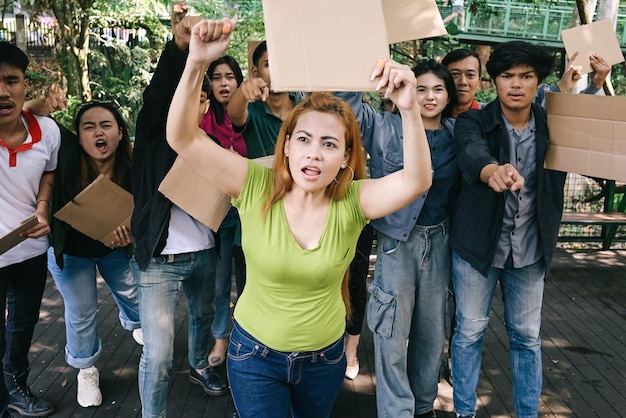 Женщина-активистка, возглавляющая демонстрации, поднимает руки и держит чистый картон.
