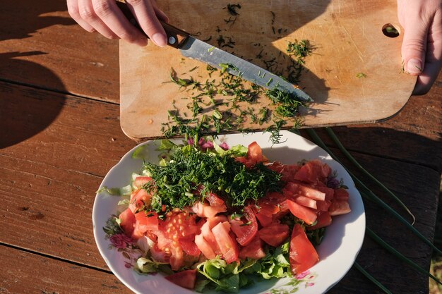 Foto la donna aggiunge l'aneto all'insalata di verdure