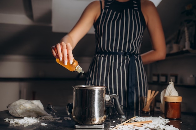 The woman adds flavoring agent to candle wax