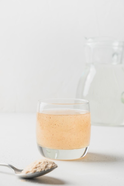 Woman adds psyllium fiber to glass of water on a white background