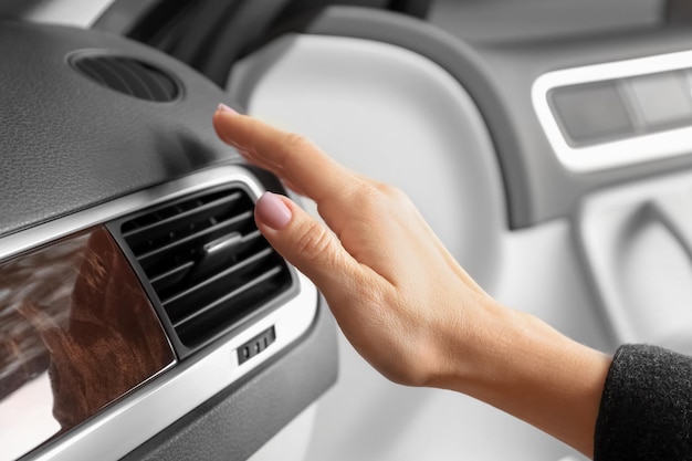 Woman adjusting air conditioner in car closeup