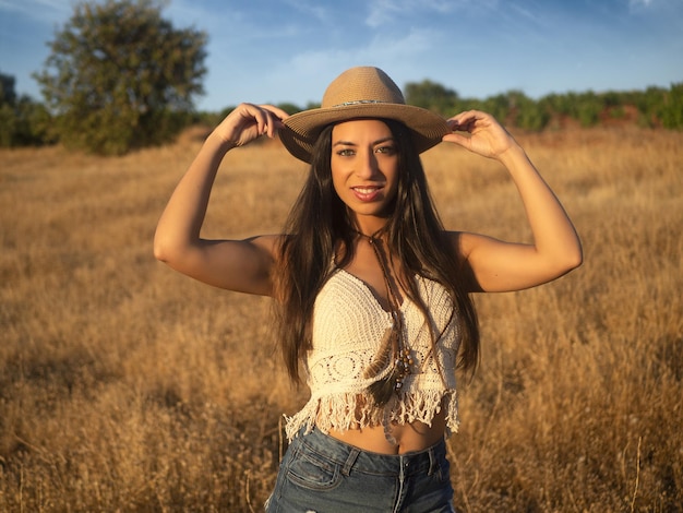 Woman adjusting hat in field