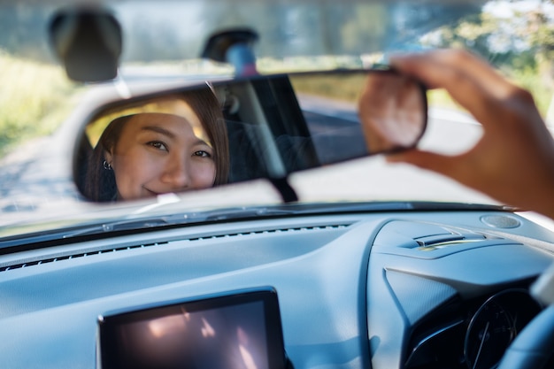 車の運転中にバックミラーを調整する女性