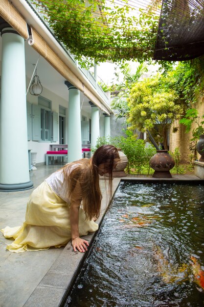 A woman admires the fish in a pond on the courtyard