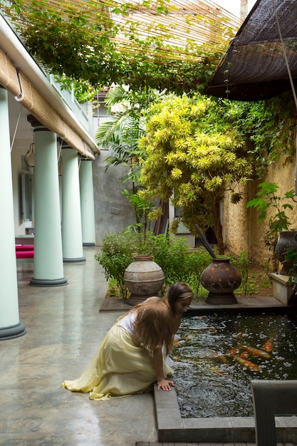 A woman admires the fish in a pond on the courtyard