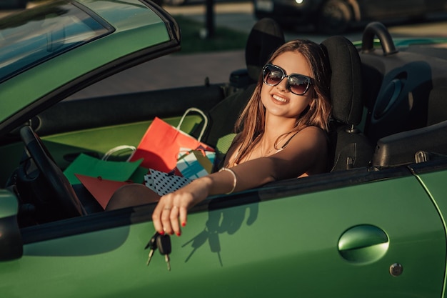 Woman after shopping sitting in car with bags