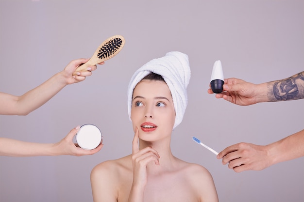 A woman after a shower looks at hygiene items.