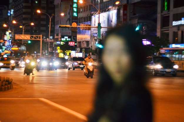 夜街の通りで照明を照らされた車両に反対する女性