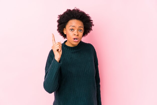 La donna contro una parete rosa ha isolato avendo un'idea, concetto di ispirazione