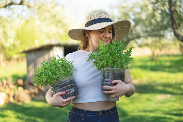 鉢植えの苗木を持った女性農学者春の植え付け窓辺の自宅の箱に植えられた苗木から育てられた初期の苗木アースデイの概念有機園芸生態学持続可能な生活