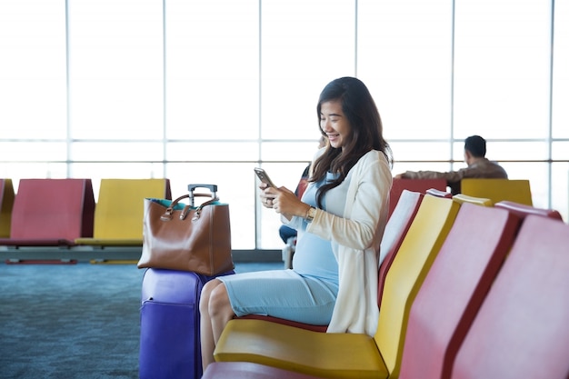 Woman in the aiport lounge sitting in chair by the window and us