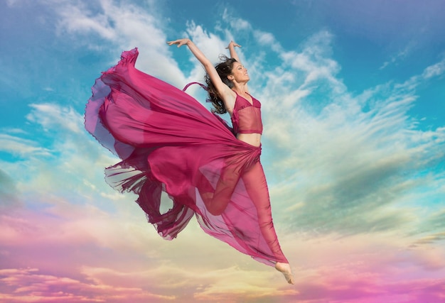 Woman in airy red dress jumping in the air