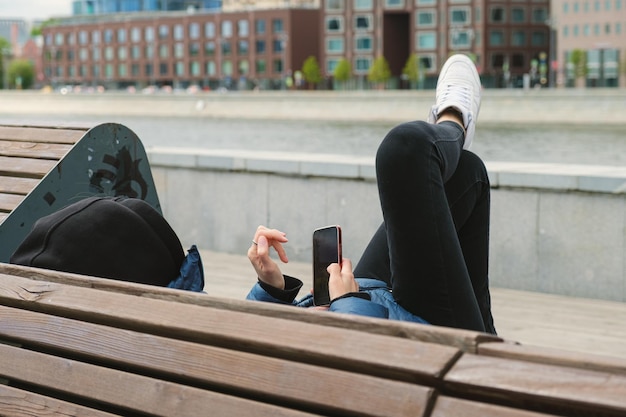 Woman alone on a bench in a city park looks at the screen of a mobile phone