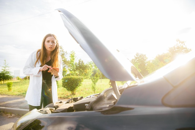 Woman alone driver checking a car engine for fix and repair problem with unhappy and dismal