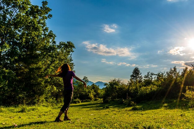 Woman amidst trees on land against sky