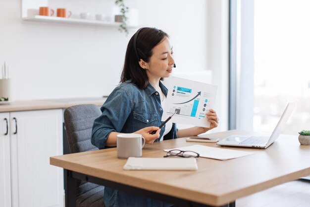 Woman analyzing graph on video conference via laptop at home