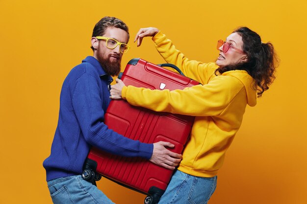 Фото Женщина и мужчина улыбаются чемоданами в руках с желтым и красным чемоданом, весело улыбаясь и криво желтом фоне, отправляясь в путешествие семейный отдых молодожены