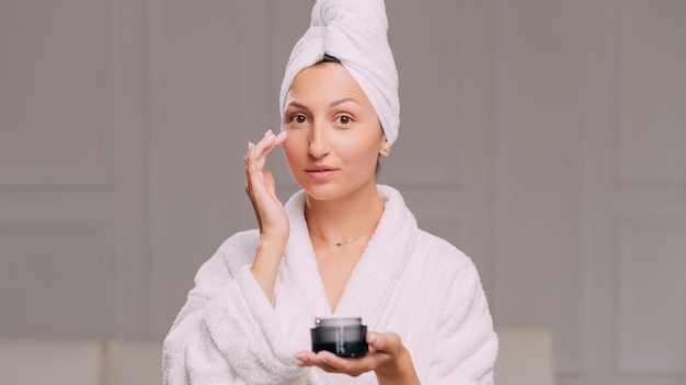 Woman applies cream to face