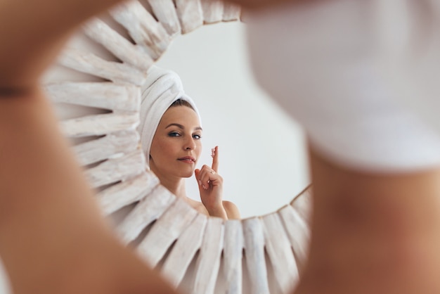 Woman applies cream to her face, moisturizes her skin.