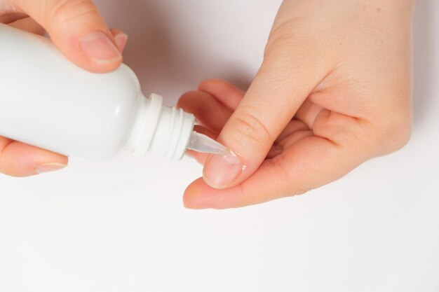 Woman applies cuticle remover to nails