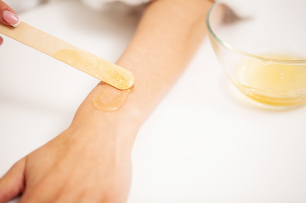 Woman applies hot wax to skin to remove hair