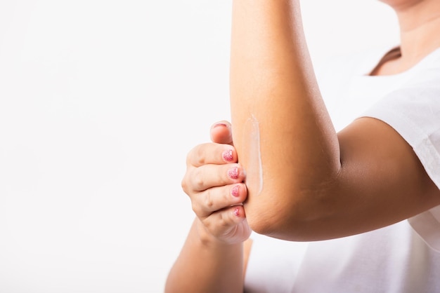 Woman applies lotion cream on her elbow